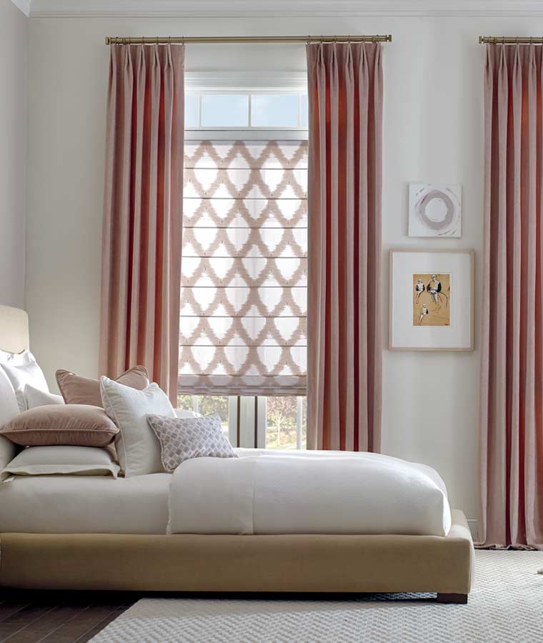 bedroom with patterned roman shades and mauve drapery